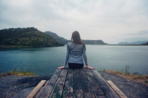 Woman sitting on dock next to a lake