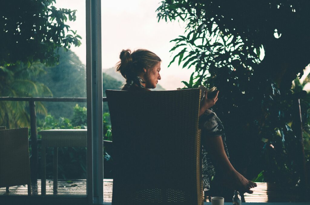 Woman relaxing on a patio surrounded by greenery, reviewing her creative side project ideas on her phone and finding work-life balance.