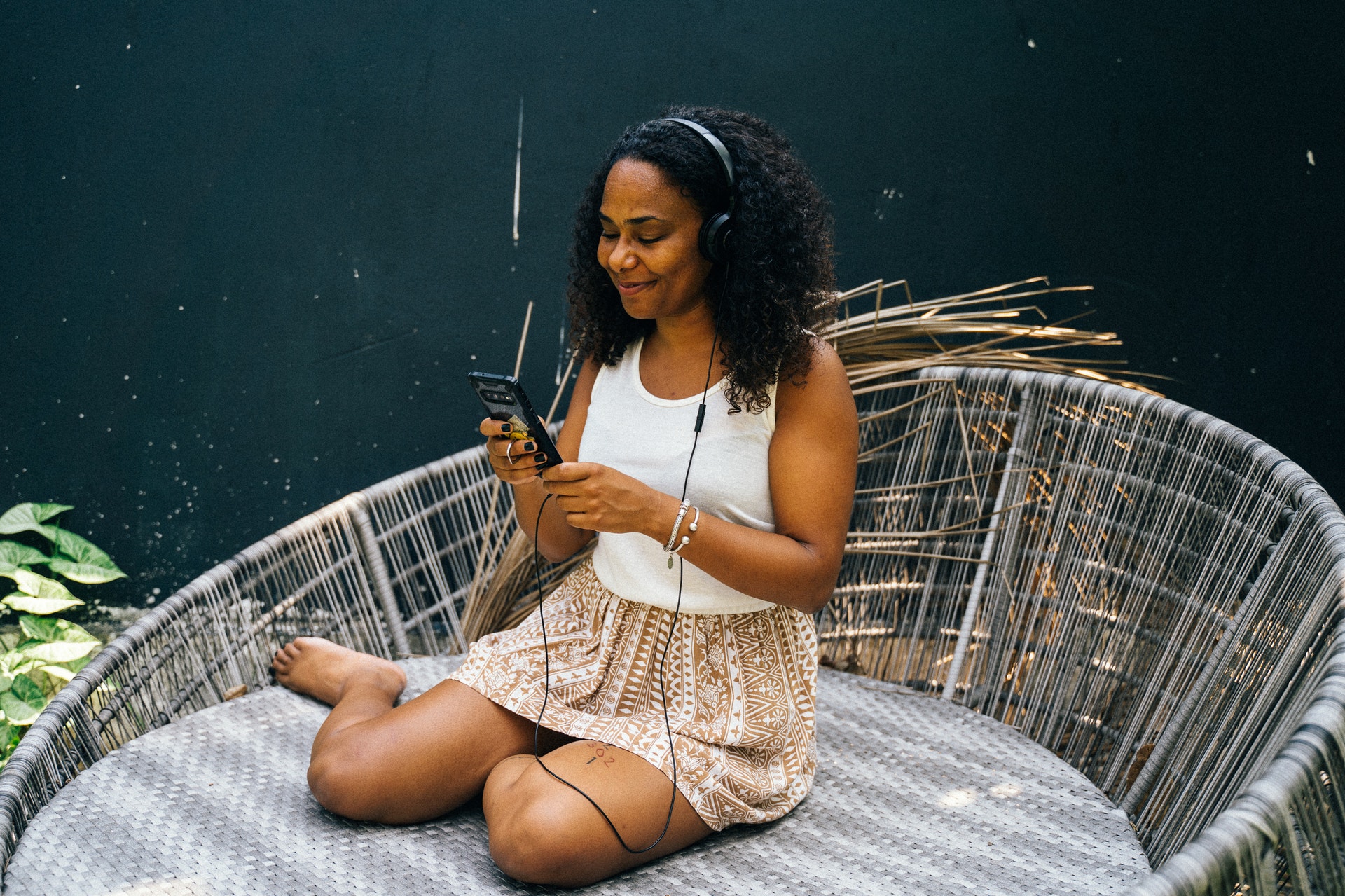 Woman sitting in chair outside listening to podcast